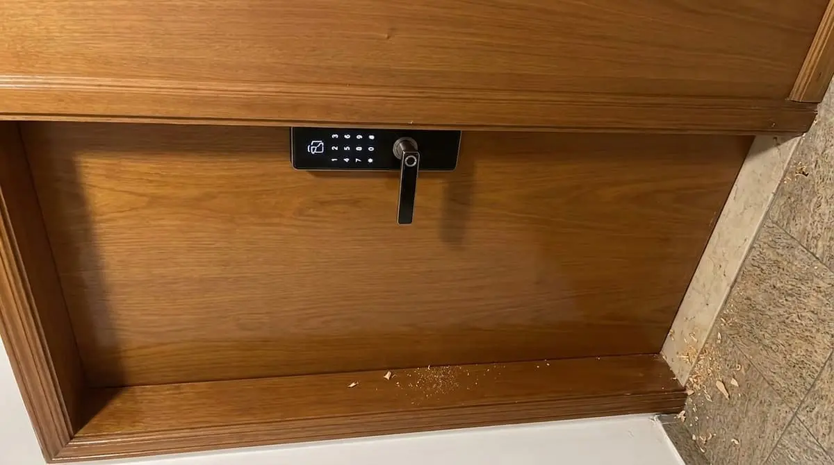 Fechadura digital instalada em porta de madeira, teclado aceso, com serragem no chão