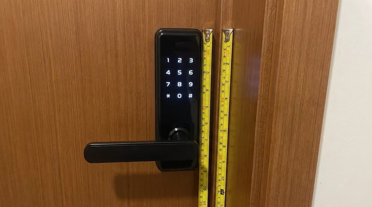 Fechadura digital preta com teclado iluminado instalada em porta de madeira de apartamento